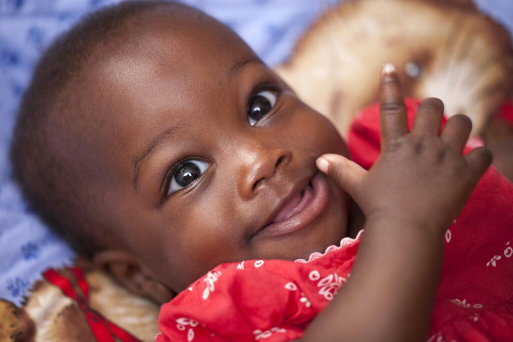 baby-child-kid-girl-161593-161593 Close-up portrait of a happy baby smiling in a bright red outfit, showcasing joy and innocence.
